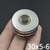 A close-up of a countersunk neodymium disc magnet with a center hole being held by a hand.