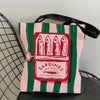 A pink and green striped canvas tote bag featuring a graphic print of sardines in olive oil.