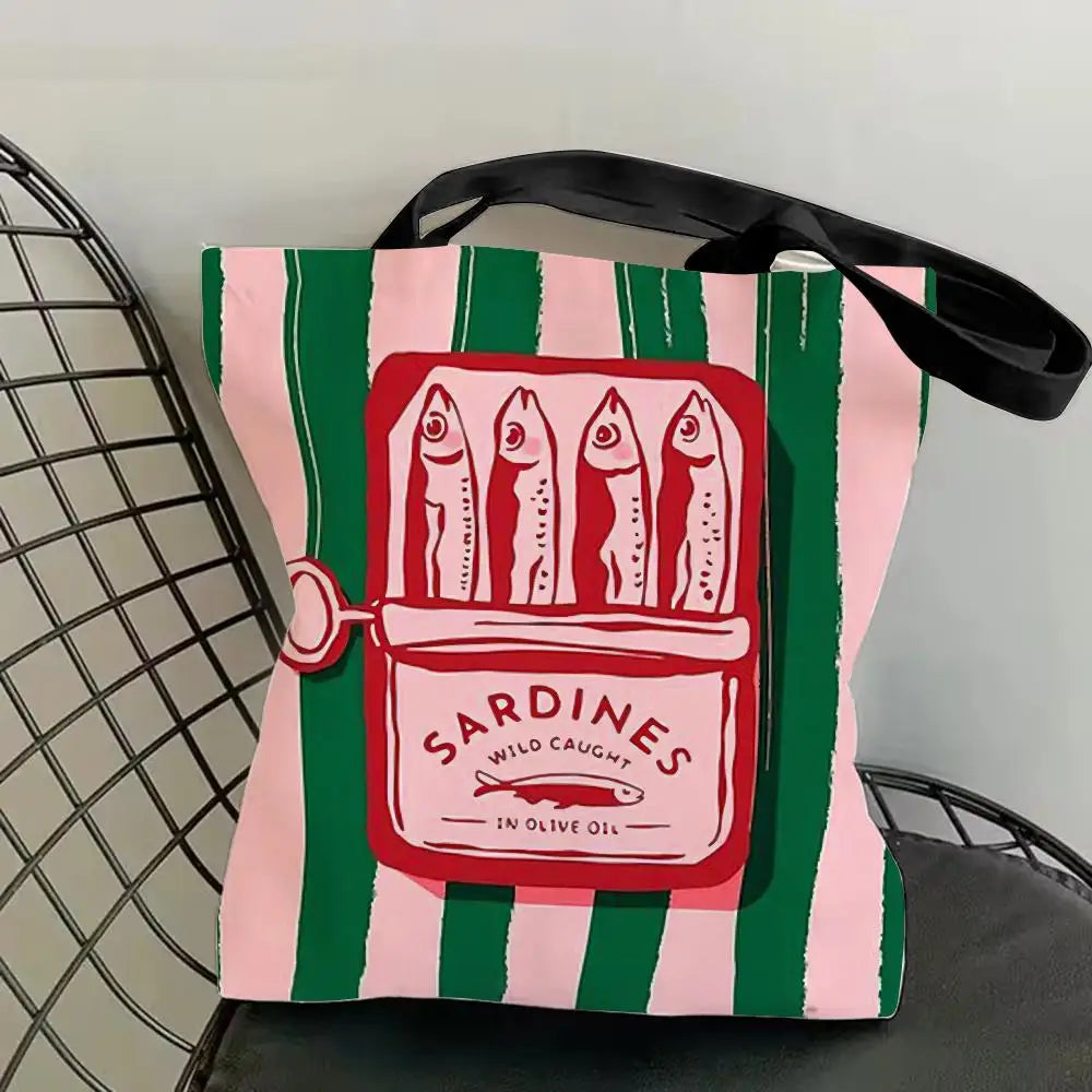 A pink and green striped canvas tote bag featuring a graphic print of sardines in olive oil.