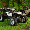 A black and white six-wheel drive off-road RC car with an alloy body parked on green grass.