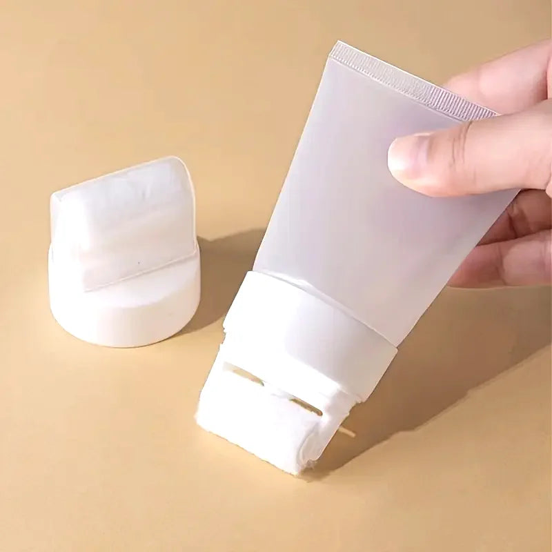 A hand holds a white wall paint repair roller with a refillable bottle and a separate white cleaning pad.