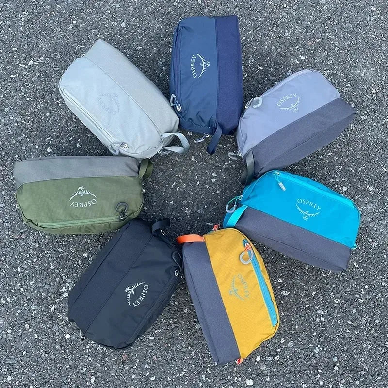 Collection de neuf sacs de toilette pliables et étanches Osprey dans diverses teintes de bleu, gris, vert et jaune éparpillés