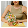 A woman holds a bouquet of cherry blossoms on a yellow card.