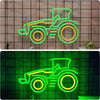 A neon sign of a tractor in green and yellow outlines is displayed against a textured wall.