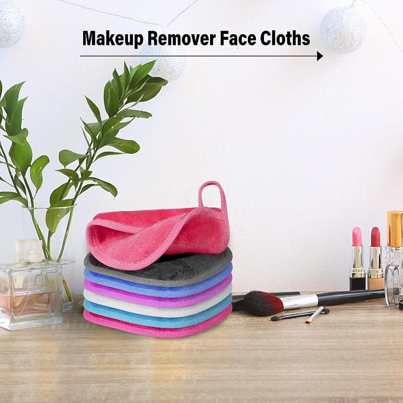 A set of five colorful reusable makeup remover face cloths stacked on a wooden surface.