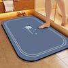 A blue bathroom mat with a white outline and a small clover design is placed on a tiled floor.