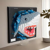 A framed wall art piece featuring a mosaic of a shark head made from blue and white building blocks.