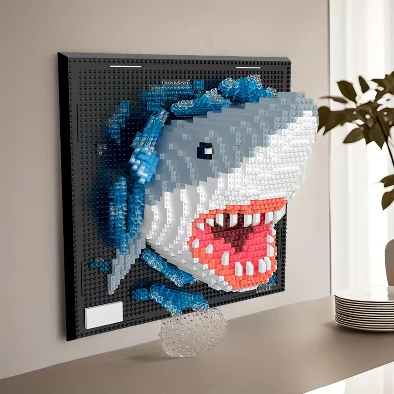 A framed wall art piece featuring a mosaic of a shark head made from blue and white building blocks.