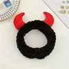 A black faux fur devil horn rearview mirror cover with red accents displayed on a white surface.