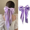 A purple silk bow hair clip tied around a ponytail holder