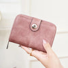 A close-up of a vintage RFID blocking short wallet with a zipper closure shown being held by hands.
