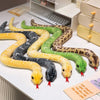 A collection of lifelike snake plush toys in various colors and patterns laid out on a white surface.