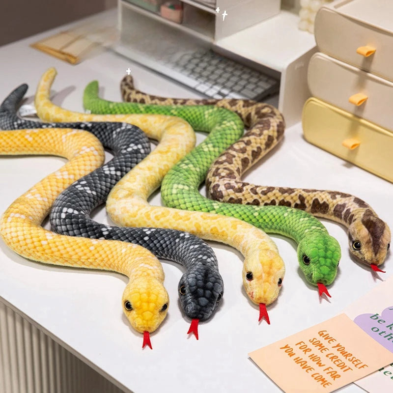 A collection of lifelike snake plush toys in various colors and patterns laid out on a white surface.