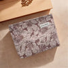 A canvas charger storage pouch with a floral pattern resting on a light wooden surface.