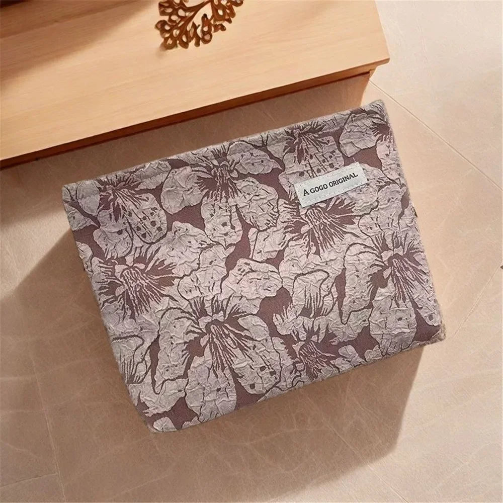 A canvas charger storage pouch with a floral pattern resting on a light wooden surface.