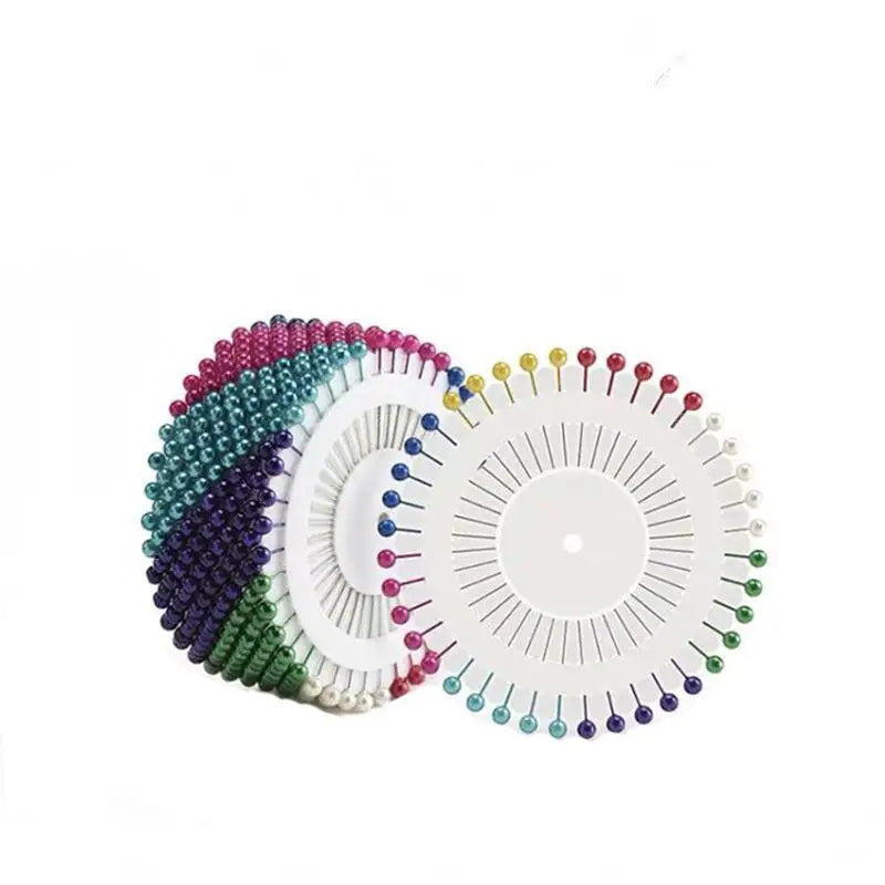 A collection of colorful round pearl straight pins in various shades arranged in a fan pattern.