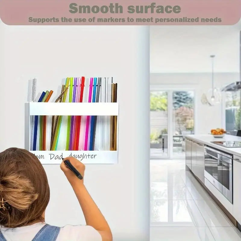 An acrylic straw dispenser with an adhesive mount is shown on a white wall, ready for use.