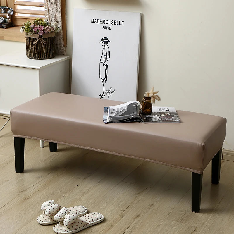A beige waterproof PU stretch bench cover is displayed on a wooden bench with a minimalist drawing of a figure on the wall.
