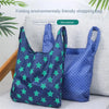 A pair of dark blue fabric shopping bags with green star patterns are displayed on a light gray surface.