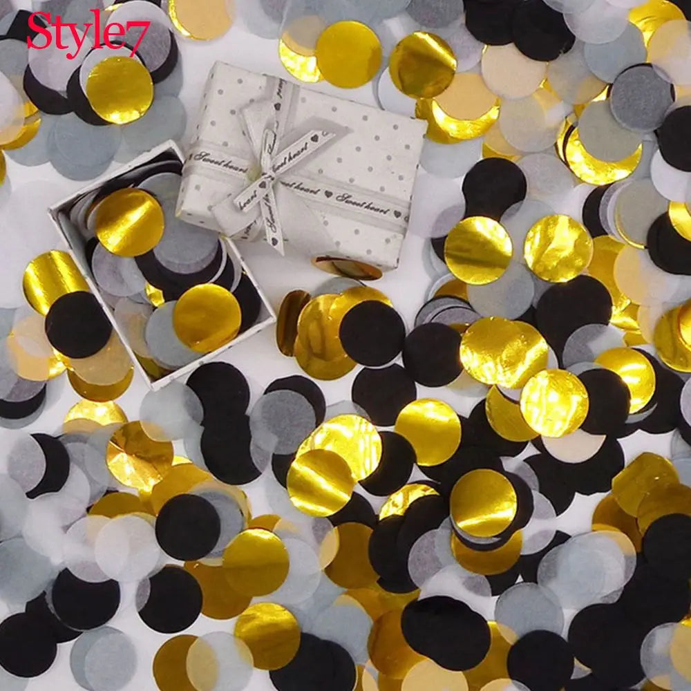 Mischung aus Gold, Silber und Schwarz-Tissuespapier-Konfetti verstreut auf einer weißen Oberfläche mit einer Geschenkbox.