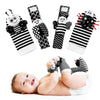 A set of soft baby rattles featuring black and white striped wrist and foot finders.