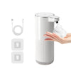 A white touchless automatic soap dispenser with a pump head and charging cable is shown next to a hand dispensing soap.