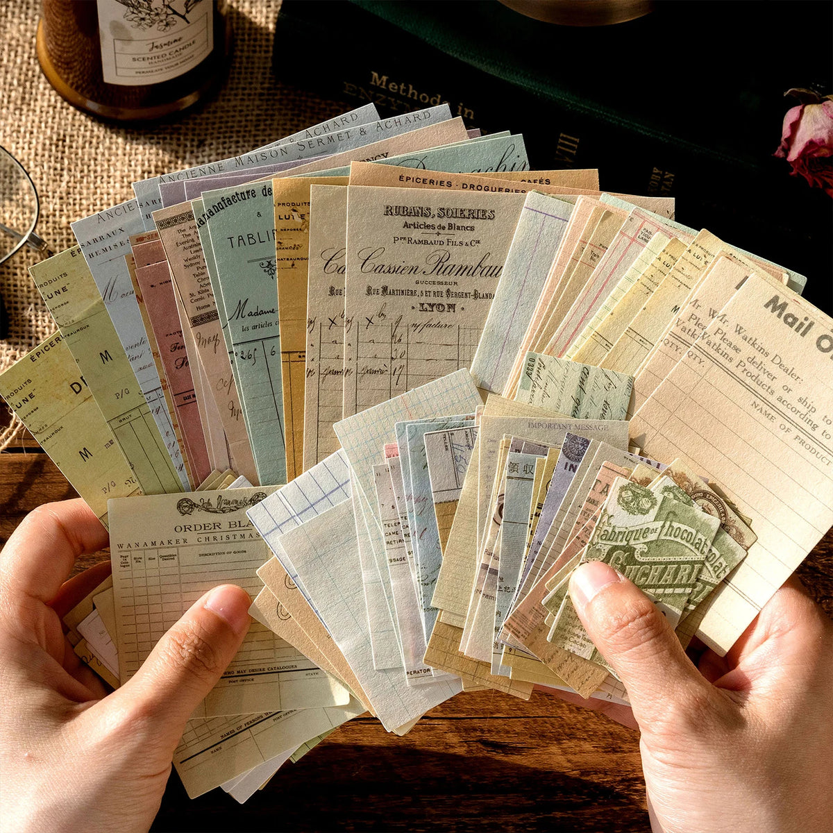 Une collection de cartes et d'étiquettes vintage tenues par une personne sur une surface en bois.