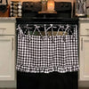 Black farmhouse plaid oven skirt with ruffled trim hanging over a black stove.