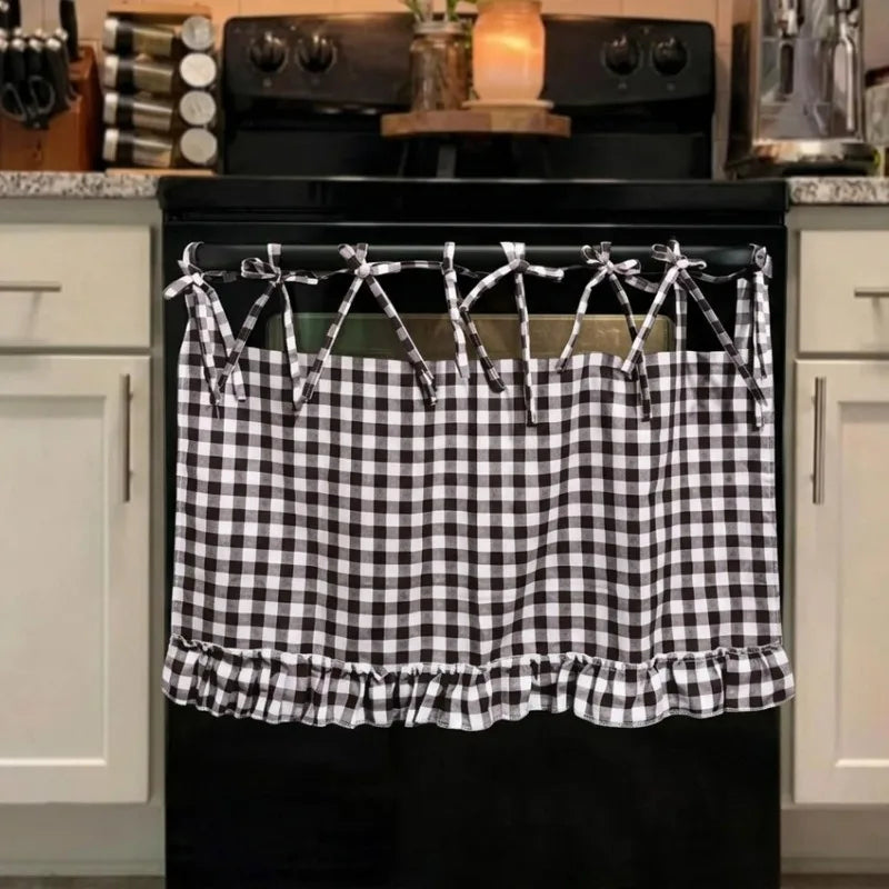 Black farmhouse plaid oven skirt with ruffled trim hanging over a black stove.