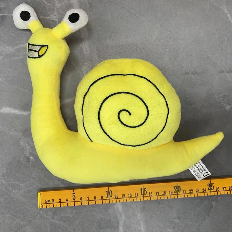 Yellow plush toy of an opila bird with large eyes and a coiled body, measured against a ruler.