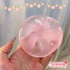 A hand holds a translucent pink squishy stress relief toy with a smooth, rounded shape.