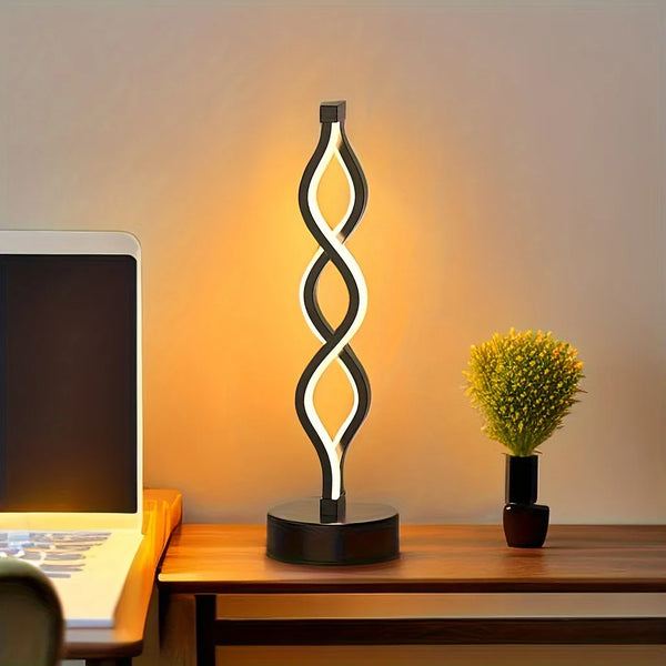A tall, black, seaweed-shaped desk lamp with a soft ambient glow illuminates a wooden desk.