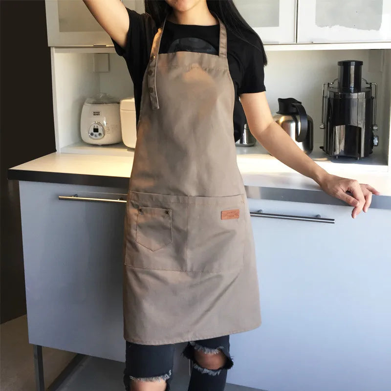 A person wearing a beige cotton apron stands in a kitchen with appliances visible.