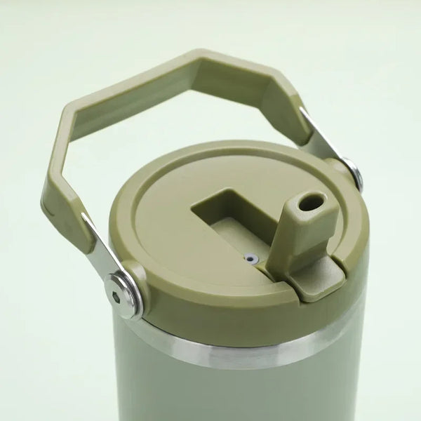 A close-up of an insulated stainless steel tumbler with a light olive green lid and handle.