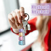 A hand holds a keychain featuring an LED macaron keyboard fidget toy.