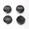 Four views of black decorative wheel covers with Audi rings on a white background.