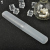 A clear plastic travel toothbrush case is shown next to several small, clear, cube-shaped objects and a glass jar containing 