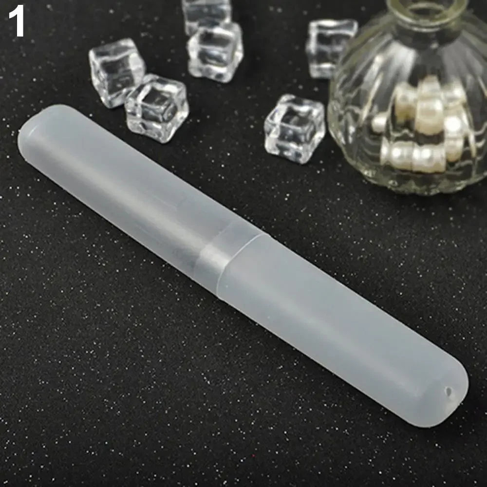 A clear plastic travel toothbrush case is shown next to several small, clear, cube-shaped objects and a glass jar containing 