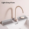 Light grey foldable silicone faucet splash mat with a curved metal faucet installed on a white sink.
