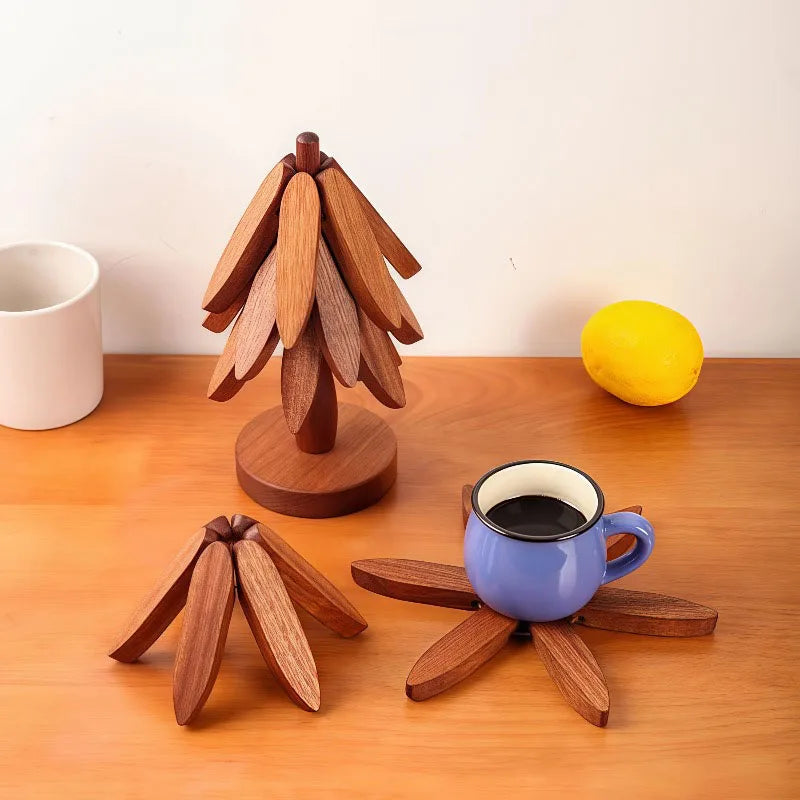 A set of wooden tree-shaped heat-resistant trivets resting on a wooden table next to a yellow lemon and a blue mug.