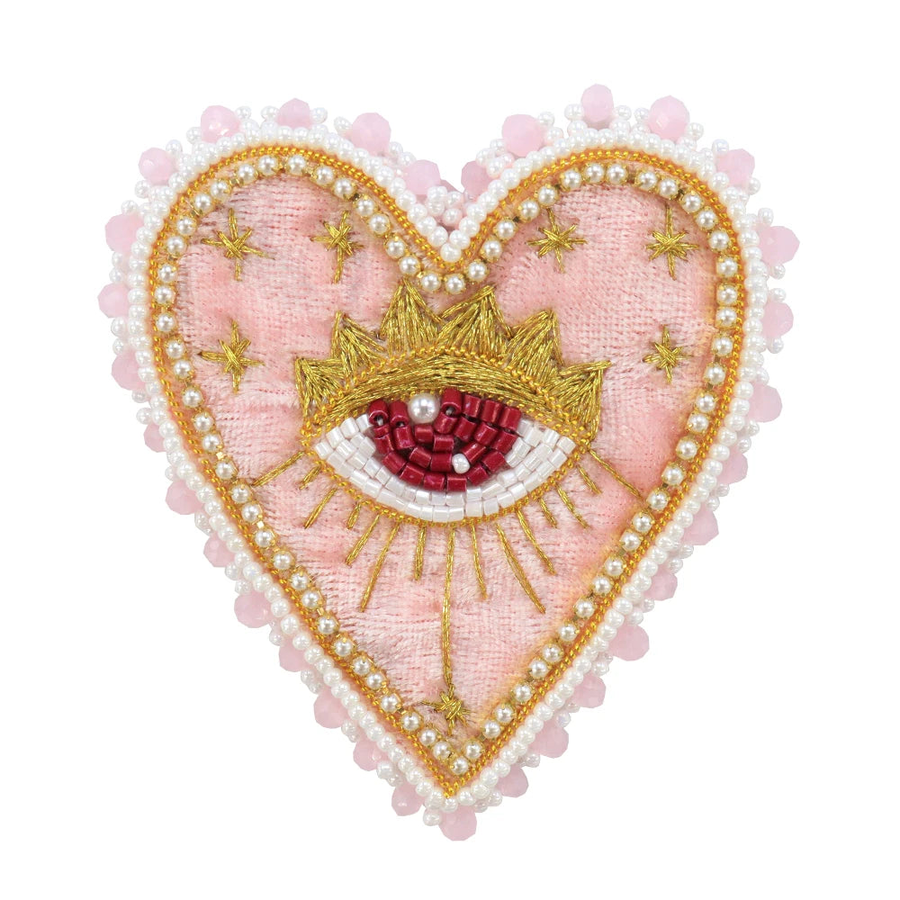 A heart-shaped patch featuring a pink fabric with a gold crown and an eye design embellished with white pearls and rhinestone