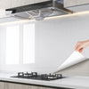 A modern kitchen setup featuring a stainless steel range hood and a black stovetop on a white countertop.
