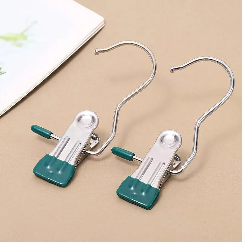 A pair of stainless steel clothespins with hooks used as a space-saving closet organizer on a beige surface.