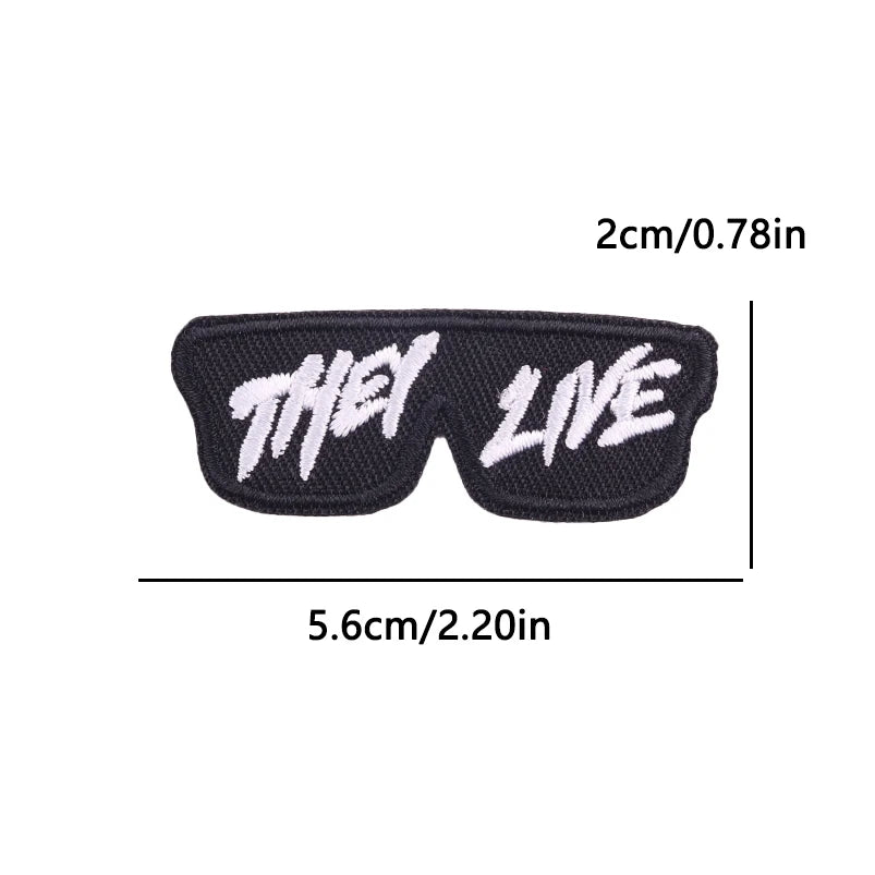 Black embroidered iron-on patch with the words THEY LIVE in white text