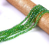 Green faceted crystal glass spacer beads strung together on a brown cylindrical object.