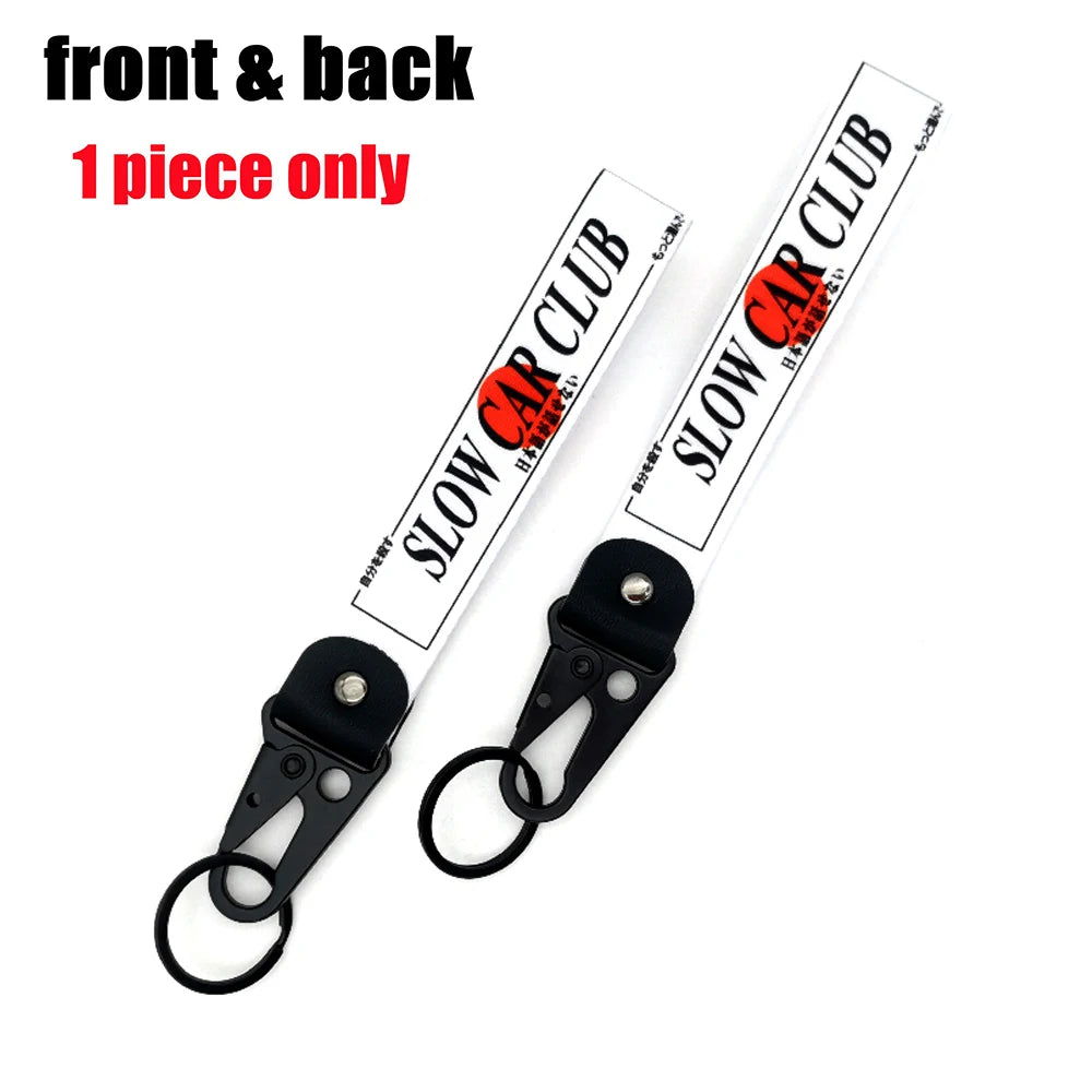 Front and back view of a Slow Car Club keychain with a steel clip.