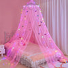 Pink sheer mosquito net dome with LED lights draped over a bed for a dreamy ambiance