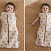 A baby wearing a beige breathable cotton sleep sack with a floral pattern and adjustable sleeves.