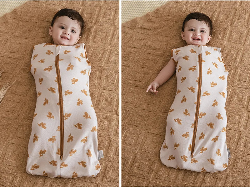 A baby wearing a beige breathable cotton sleep sack with a floral pattern and adjustable sleeves.