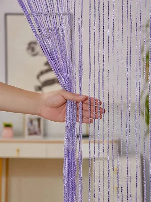 A hand is pulling a long, purple tassel string curtain down, showing the delicate strands and texture.